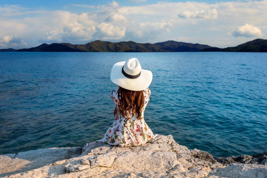 young-woman-sitting-top-rock-looking-seashore (1)