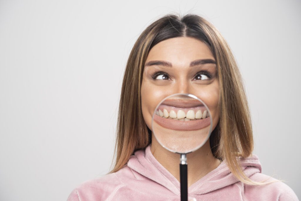 Girl in pink swaetshirt putting a magnifier to her mouth. High quality photo